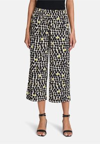 Zwart-wit gemusterde cropped broek met een aquarelachtig ontwerp en accenten van limoen groen. Met een elastische tailleband voor comfort.