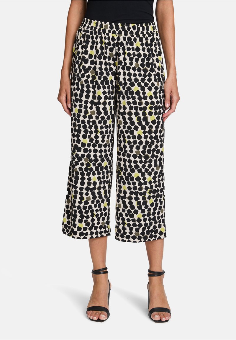 Zwart-wit gemusterde cropped broek met een aquarelachtig ontwerp en accenten van limoen groen. Met een elastische tailleband voor comfort.