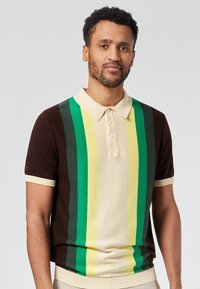 Camiseta de polo de punto con rayas horizontales en tonos de marrón, verde y amarillo. Con cuello, cierre de botones y puños acanalados.
