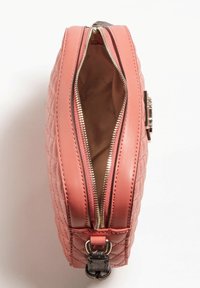 Prošívaná kabelka z korálové kůže se zlatým zipem. Má hladý interiér a kulatý tvar s boční kovovou smyčkou.