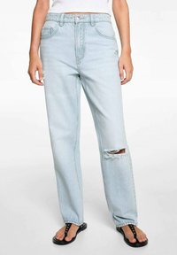 Jeans in denim azzurro chiaro con vestibilità rilassata, caratterizzati da un dettaglio strappato sul ginocchio destro e design classico a cinque tasche.