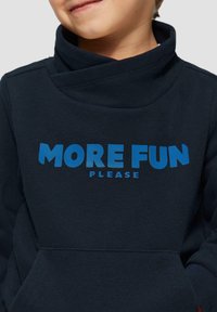 Marine blauwe sweatshirt met een kraag in funnelstijl, voorzien van een grote blauwe print met de tekst "MEER PLEZIER ALSJEBLIEFT" en een zak aan de voorkant. Zachte stof.