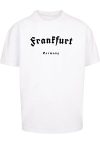Hvit bomulls t-skjorte med "Frankfurt" i fet svart gotisk stil og "Tyskland" nedenfor i mindre svart tekst. Korte ermer og rund hals.