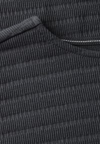 Tissu texturé gris foncé avec un motif de nervures verticales. Matériau doux et extensible avec un subtil brillant et un fin détail de couture.