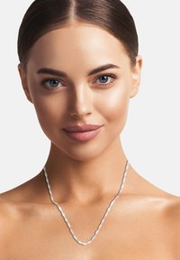 Sølv snoet kædedesign hviler p å huden, med et delikat design og en glat, reflekterende overflade.