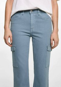 Svetlomodré cargo nohavice s bočnými vreckami, s priliehavým pásom, rovnými nohavicami a hladkou denimovou textúrou. Zapínanie na kovový gombík.