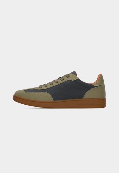 Sneaker dal profilo basso in pelle verde oliva e pannelli in tessuto nero, suola in gomma marrone e lacci verde oliva su sfondo bianco.