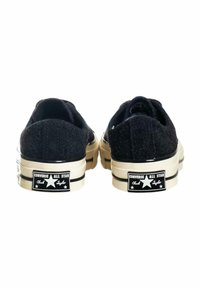 Sneakers Converse Chuck Taylor in tela nera con finitura testurizzata, suola in gomma color avorio e marchio classico sul tallone.