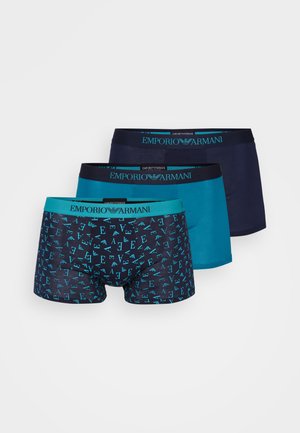 Tres pares de bóxers para hombres en tonos azules. Uno presenta un patrón de logotipos, mientras que los otros son de un azul oscuro sólido y un verde azulado, con cinturillas con logotipos.