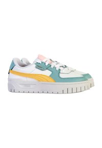 Zapatilla con una base blanca, acentos en azul verdoso y amarillo, materiales texturizados y una suela blanca gruesa. Presenta un diseño de cordones y lengüetas coloridas.