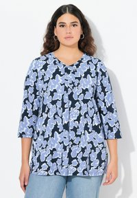 Sininen ja valkoinen kukkakuosiset paita, jossa on kolmanneksen hihat, V-pääntie ja tilava istuvuus. Valmistettu kevyestä kankaasta, jossa on sileä tekstuuri.