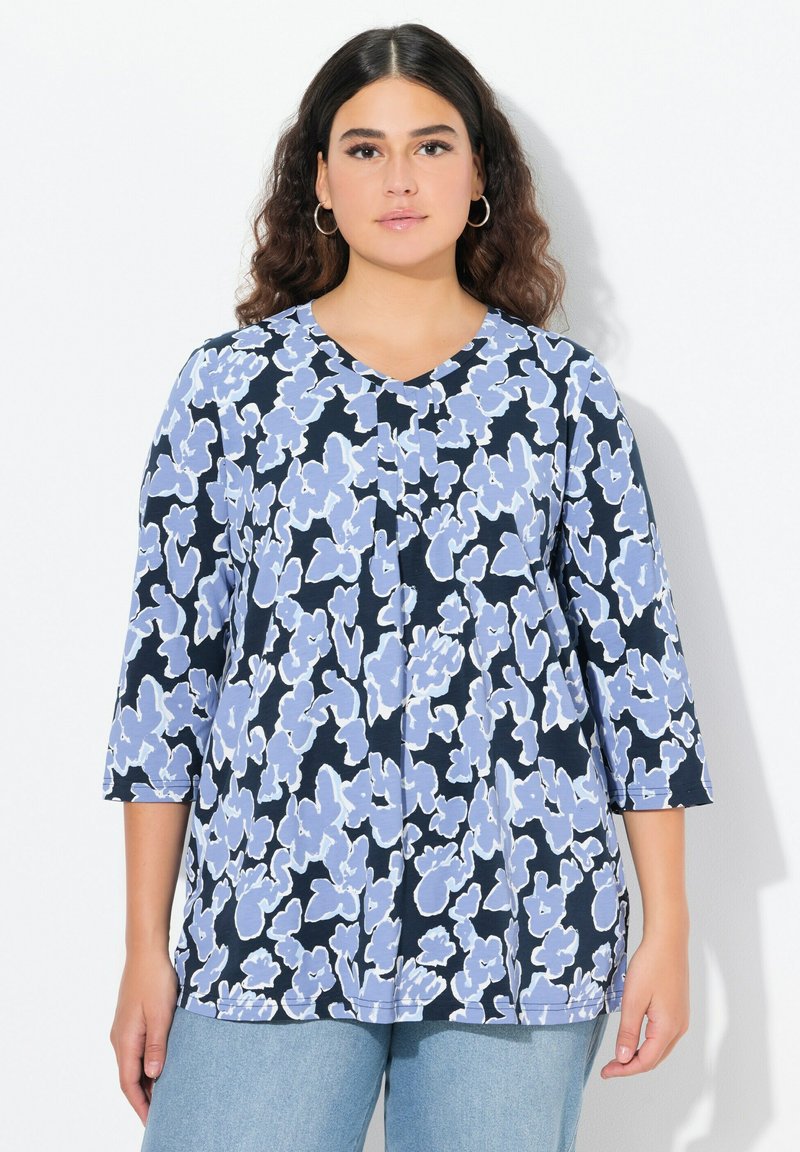 Sininen ja valkoinen kukkakuosiset paita, jossa on kolmanneksen hihat, V-pääntie ja tilava istuvuus. Valmistettu kevyestä kankaasta, jossa on sileä tekstuuri.