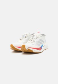 Weiße Sportschuhe mit einem atmungsaktiven Mesh-Obermaterial, grauen Akzenten, einem rot-blauen Design an der Seite und einer Sohle aus Gummirubber.