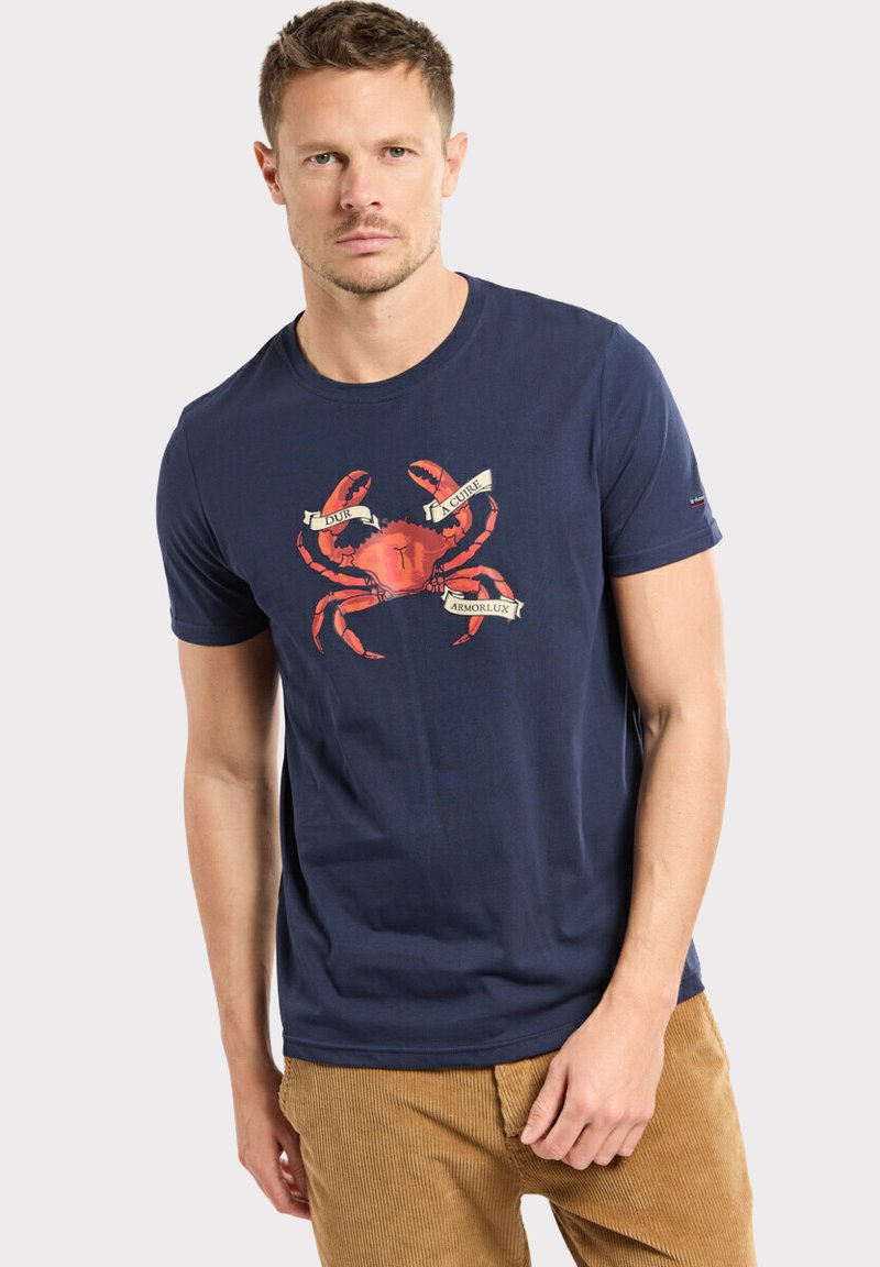 T-shirt en coton bleu marine avec un graphisme d'un crabe rouge et des rubans de texte. Manches courtes et col rond, coupe décontractée.