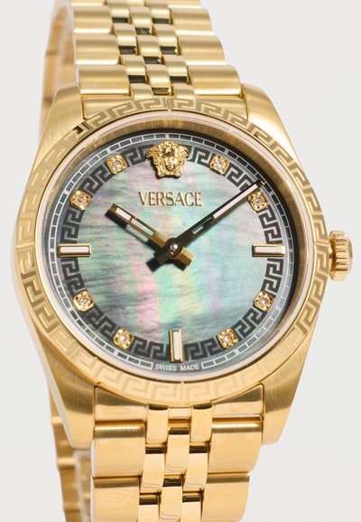 Χρυσό ρολόι χειρός Versace με μαύρο και χρυσό καντράν, διαμαντένιους δείκτες ώρας, λογότυπο Medusa στις 12 και μεταλλικό μπρασελέ με κρίκους.