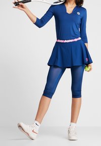 Námořnické sportovní šaty s výstřihem do V, dlouhými rukávy, vrstvenou sukní a růžovým elastickým pasem. Doplněné námořnickými legínami a bílými teniskami.