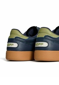 Zapatillas de cuero marinas con acentos verdes, parte trasera texturizada y suela de goma. Presenta un logo blanco en el lateral.