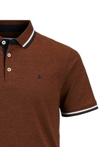Bruine polo met een gestructureerde stof, drie-knopen sluiting, contrasterende marineblauwe kraag, en gestreepte accenten op de mouwen.