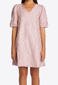 Różowa mini sukienka w kwiatowy wzór z dekoltem w kształcie litery V, krótkimi bufkami i teksturowanym materiałem. Szczegóły obejmują luźny krój i subtelny połysk.