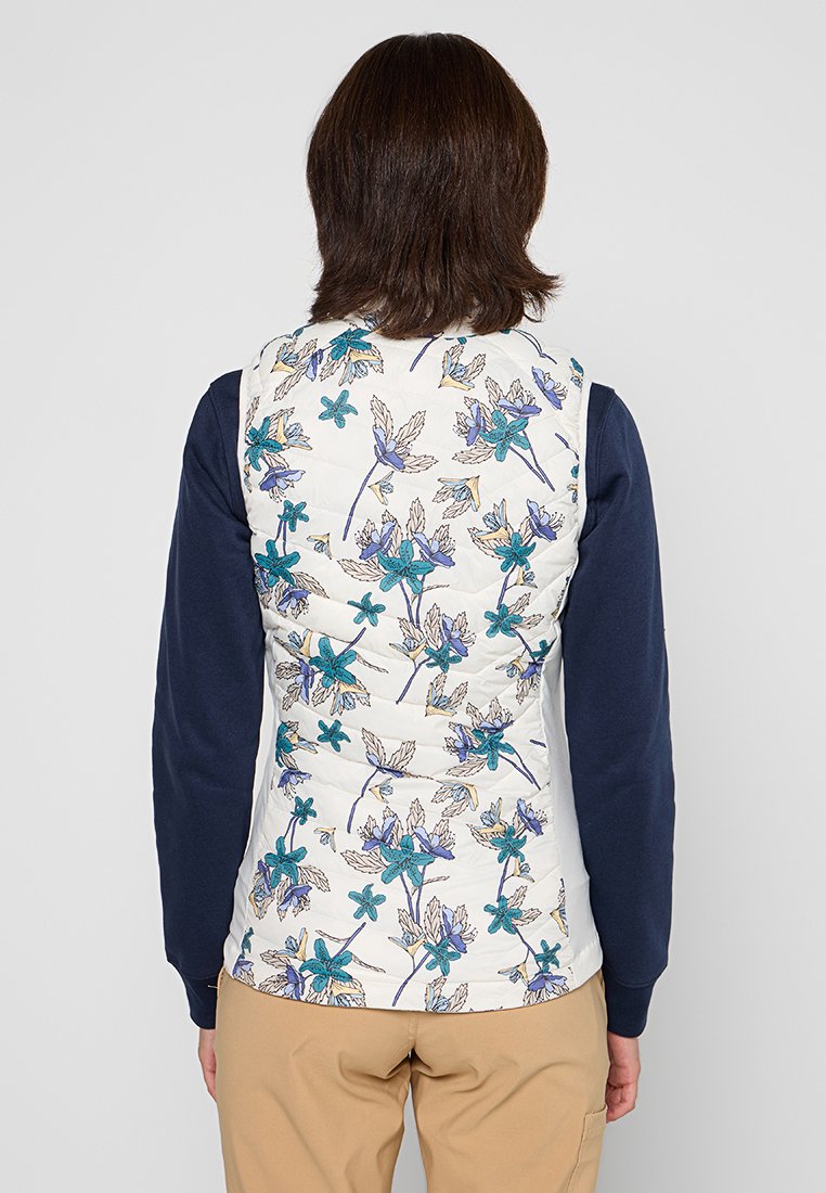 Chaleco acolchado en crema con un patrón floral que presenta detalles en azul y morado. Mangas en azul marino; tejido ligero y transpirable.