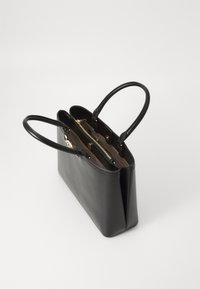 Black leather tote bag with two long handles, a smooth texture, and gold hardware. Inside features a zip pocket and multiple compartments.