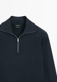 Pull bleu marine foncé à demi-fermeture éclair avec un col montant, en 100 % coton, avec une fermeture éclair argentée et une texture de tricot lisse.