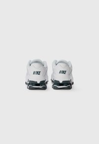 Hvide Nike sneakers med grå accenter, der har en glat overdel, mesh-foring og en flerlaget sort og hvid sål.