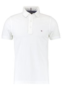 Chemise polo blanche à manches courtes, patte de boutonnage à trois boutons, petit logo brodé sur la poitrine et col classique. Texture en coton.