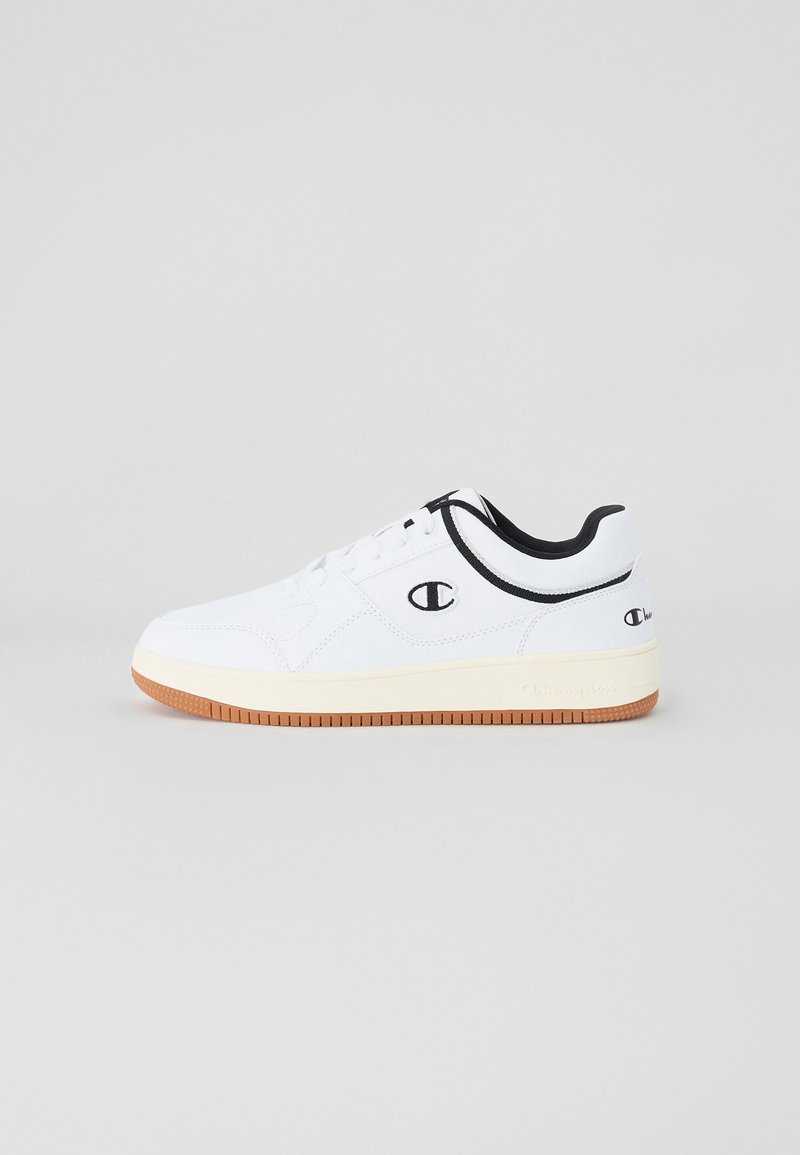 Vit sneaker med ett mjukt oväxt, svarta accenter på kragen och logotypen, samt en gummigummi yttersula. Snörningsdesign, rund tå.
