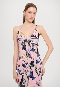 Rožinė suknelė su spageti diržais, su mazgo detale krūtinėje, ir mišriomis juodomis bei mėlynomis gėlių raštais ir tekstu.