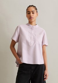 Lichtroze gestreepte shirt met korte mouwen, een mandarin kraag, knoopsluiting en een borstzak, gecombineerd met zwarte broek.