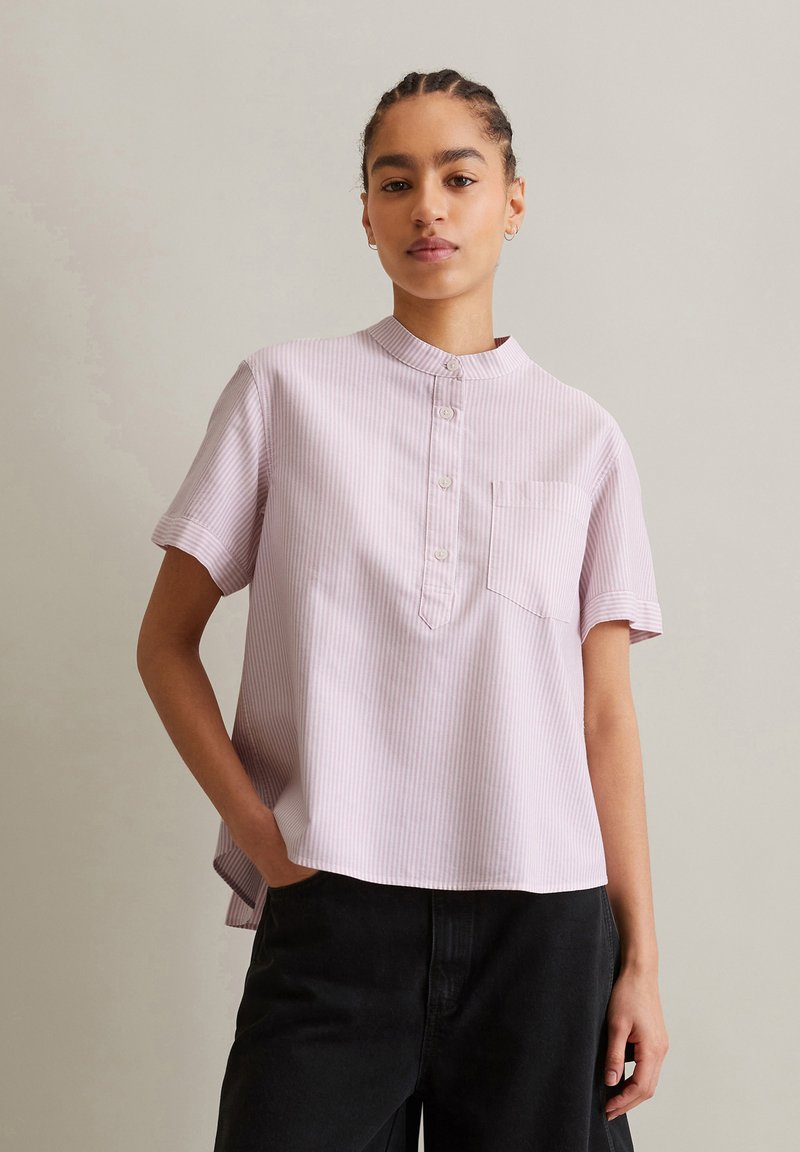 Lichtroze gestreepte shirt met korte mouwen, een mandarin kraag, knoopsluiting en een borstzak, gecombineerd met zwarte broek.