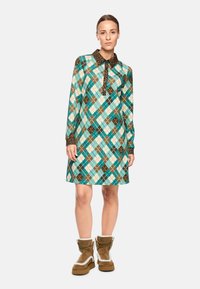 Langärmliges Kleid mit einem türkisfarbenen, braunen und weißen Argyle-Muster, das einen Kragen aus Leopardenmuster und eine geknöpfte Leiste aufweist.