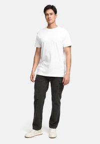 Hvid kortærmet t-shirt lavet af bomuld, parret med mørke, strukturerede cargo-bukser og hvide sneakers, med sidelommer og lige snit.