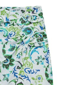 Tela con estampado floral en tonos verdes y azules sobre un fondo gris claro; presenta un diseño anudado y acentos doblados. Se ve la etiqueta de la marca.