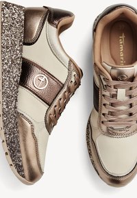 Scarpe sportive in beige e bronzo con una finitura metallica. Presentano una suola marrone glitterata e texturizzata, punta tondeggiante e lacci frontali.