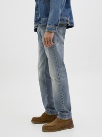 Svetlo modri denim kavbojki s ravnim vplivom, ki imajo obrabljene detajle in zbledel izgled. Nosijo se z rjavimi semiš čevlji.