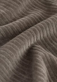 Textured fabric in a soft, muted gray. Features a wave pattern across the surface, highlighting a plush, tactile quality.
