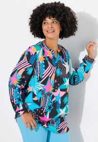 Top a maniche lunghe colorato con un mix di motivi geometrici, inclusi stelle e raggi di sole, su uno sfondo nero. Tessuto leggero e vestibilità ampia.
