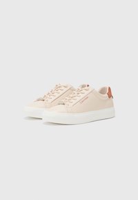Sneaker rosa chiaro realizzati in materiale liscio con suole in gomma bianca, caratterizzati da un design con lacci e un accento color tan sul tallone.