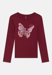 Burgundy pitkähihaisen paidan etuosassa on pinkeistä, sinisistä ja kultaisista kukista tehty perhonen, ja kultakirjaimin sana "Love".