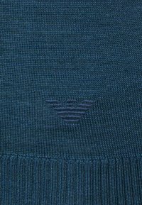 Dark blue knitted fabric with a small embossed logo resembling a bird with outstretched wings in the center.