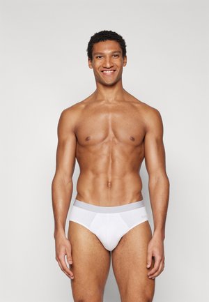 Weiße Shorts aus glattem, dehnbarem Material mit einem grauen Elastikbund. Die Passform ist eng anliegend und sorgt für Komfort und Unterstützung.