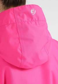  Jasně růžová bunda s kapucí pohledem zezadu, ukazující švy a malé stříbrné logo blízko vrchního středu.