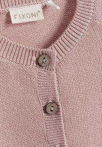 Blady różowy sweter z ribbowanym dekoltem, z trzema ciemnoszarymi guzikami z przodu i drobną, miękką strukturą dzianiny. Widoczna metka FIXONI.