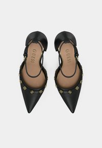 Crne kožne slingback cipele s šiljastim vrhovima, metalik detaljima i ukrasnim zlatnim hardverom oko gležnja. Mekani bež uložak.