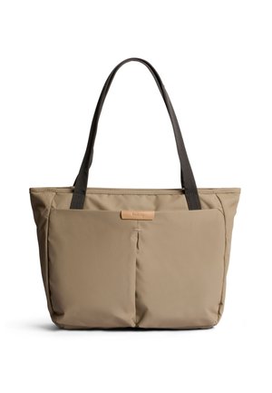 Borsa tote beige con due tasche frontali e manici scuri, design minimalista adatto all'uso quotidiano o ai viaggi.