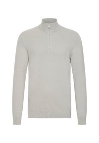 Grå strikket genser med høy krage og halvlukking. Har lange ermer og ribbestrikkede mansjetter og linning. Glatt tekstur, minimal design.