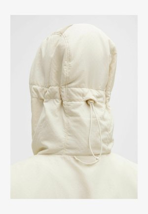Padded hooded jacket in light beige. Features a cinched drawstring at the neck, with textured outer fabric and stitching details.