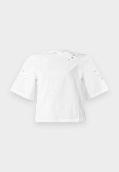 Λευκό μπλουζάκι με κοντά μανίκια και φαρδιά μανίκια με μικρά διακοσμητικά σχέδια φύλλων στους ώμους και τα μανίκια.